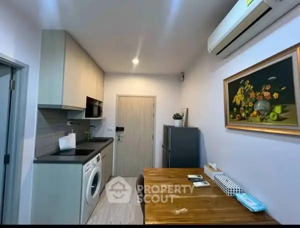 Modern kitchen with washing machine, fridge, and wooden dining table in cozy apartment.