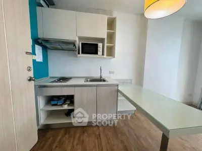 Modern compact kitchen with sleek cabinetry and built-in microwave in a cozy apartment.