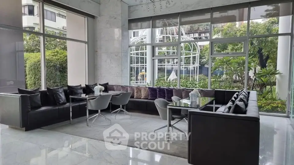 Luxurious modern living room with large windows and garden view, featuring sleek black sofas and elegant decor.