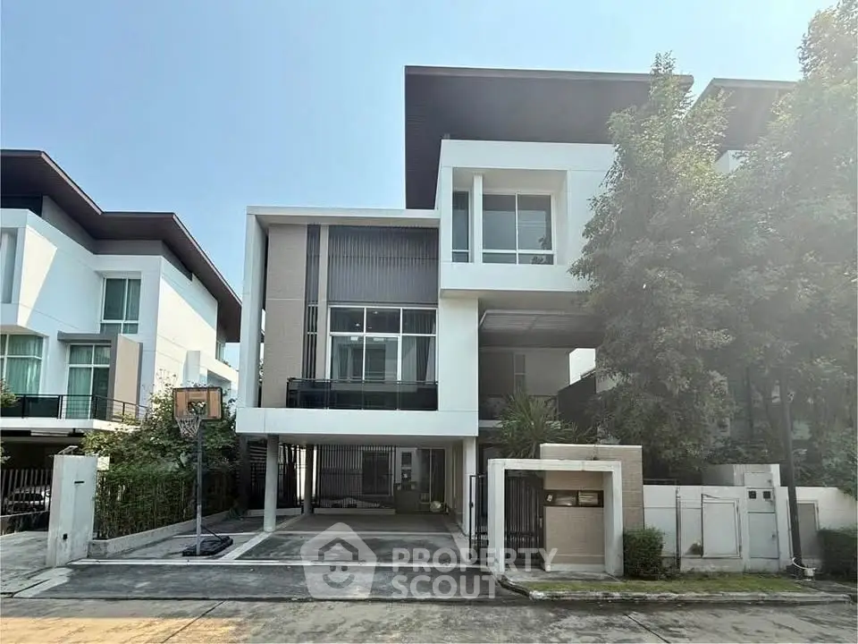 Modern three-story house with sleek design and spacious driveway in a serene neighborhood.