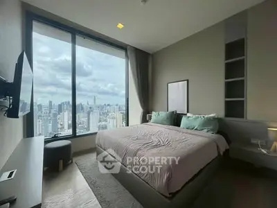 Luxurious bedroom with stunning city skyline view from floor-to-ceiling windows.