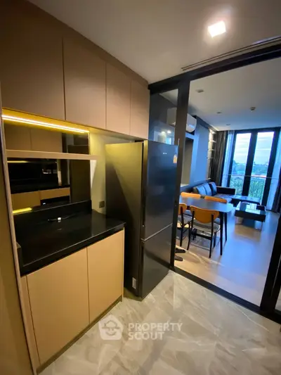 Modern kitchen with sleek design and open layout leading to stylish living room with scenic view.