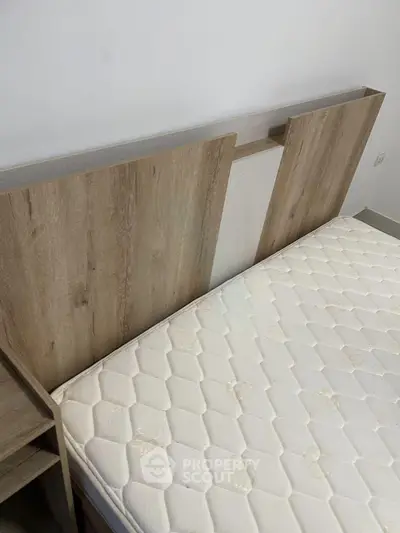 Modern bedroom with stylish wooden headboard and comfortable mattress, perfect for a cozy retreat.