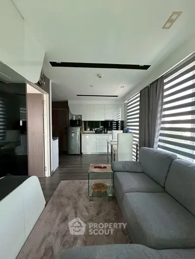 Modern open-plan living room with sleek kitchen and large windows for natural light.