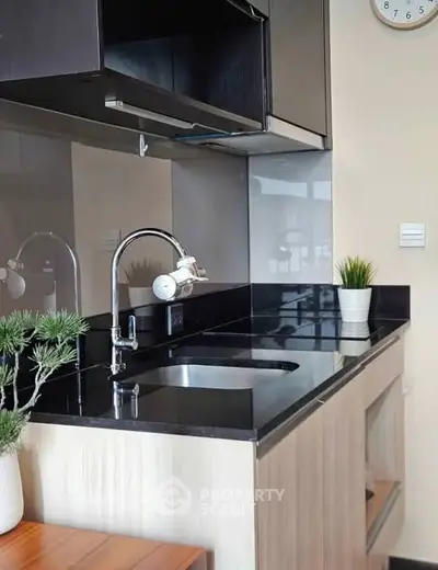 Modern kitchen with sleek black countertops and stylish fixtures in a contemporary apartment.