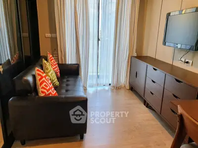 Cozy living room with modern sofa, colorful cushions, and sleek TV setup.