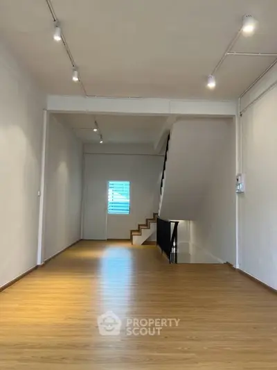 Spacious interior with wooden flooring and modern lighting, ideal for versatile living or office space.