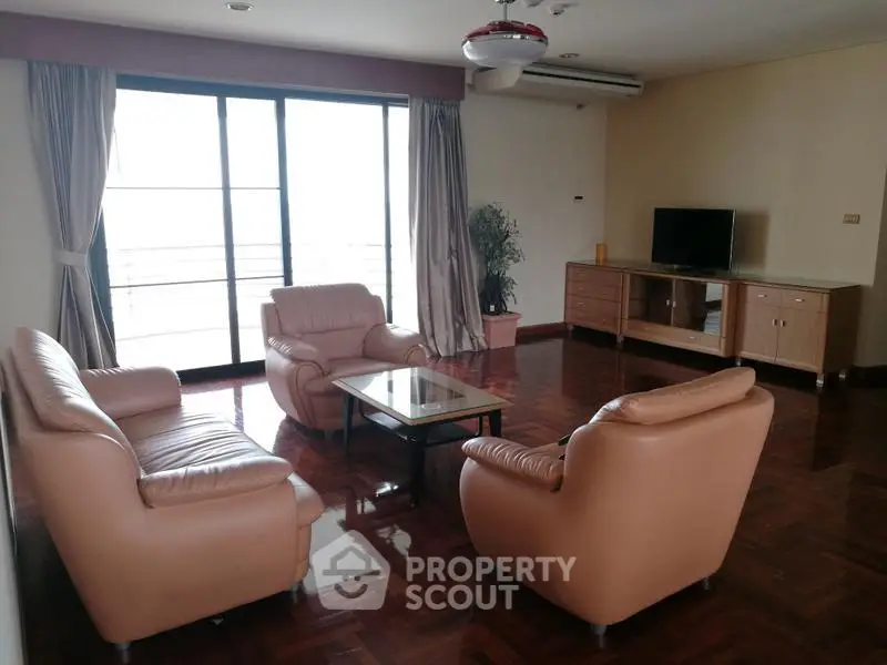 Spacious living room with leather sofas and large windows offering natural light.