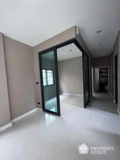 Spacious and modern living area with glossy white floors and large glass doors leading to a bright, airy space, perfect for contemporary living.