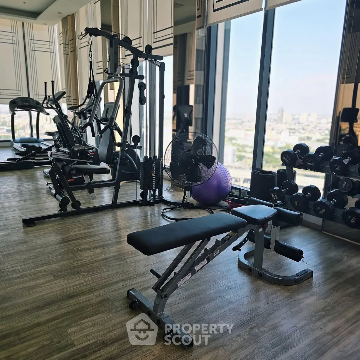 Modern gym with city view, featuring state-of-the-art fitness equipment and large windows for natural light.