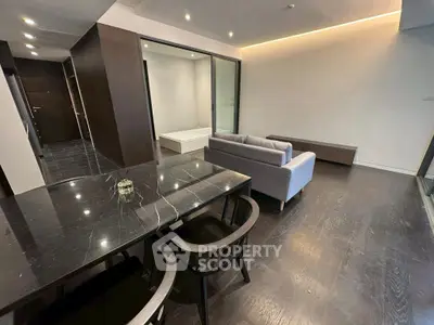 Modern open-plan living room with sleek black dining table and cozy gray sofa