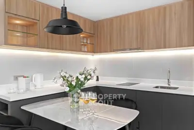 Modern kitchen with sleek design, featuring wooden cabinets, marble countertop, and elegant lighting.
