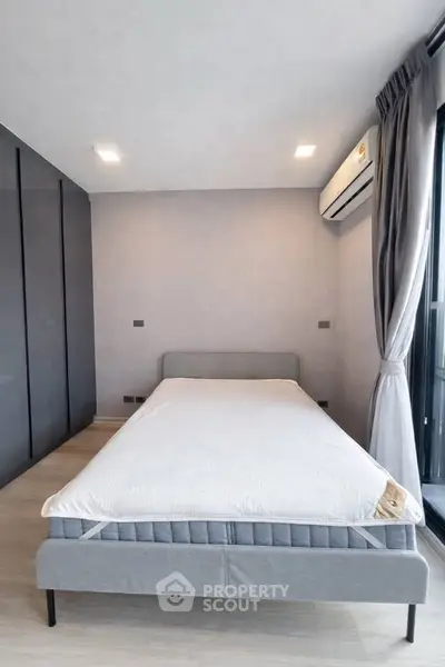 Modern bedroom with minimalist design and large window for natural light.