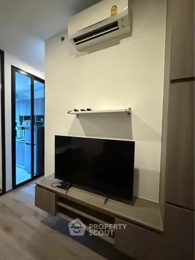 Modern living room with sleek TV setup and air conditioning in a stylish apartment.