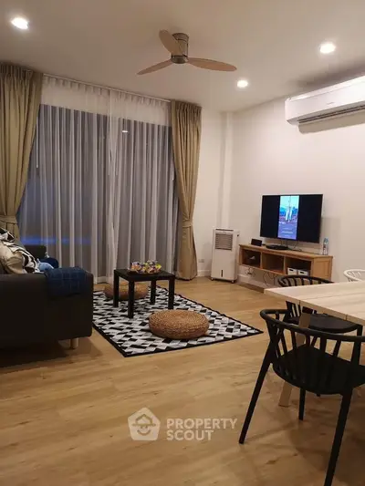 Modern living room with stylish decor and cozy ambiance, featuring a ceiling fan and entertainment setup.