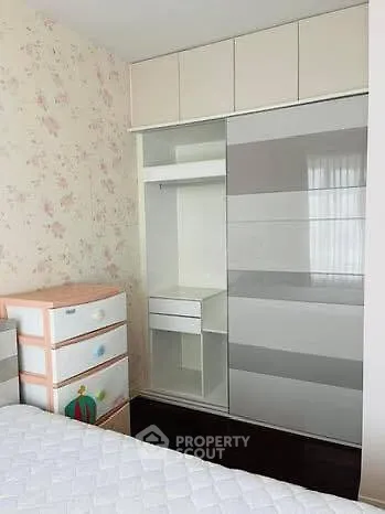 Charming bedroom with built-in wardrobe and floral wallpaper, perfect for cozy living.