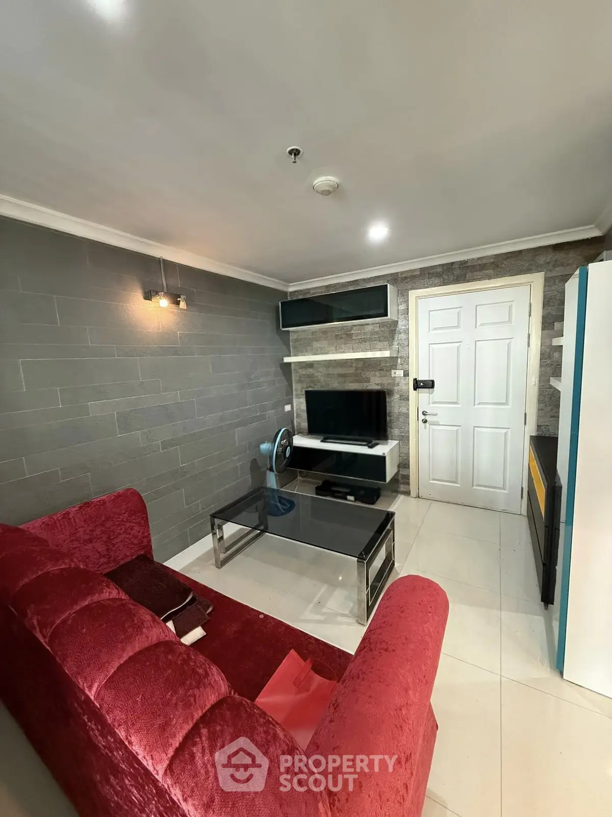 Cozy living room with modern decor and plush red sofa, perfect for relaxation and entertainment.