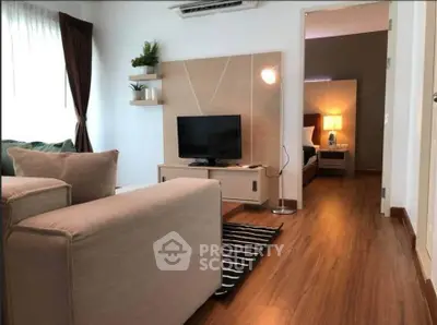 Modern living room with cozy seating and stylish decor leading to a serene bedroom.