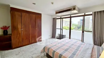 Spacious bedroom with large windows and city view, featuring elegant wooden wardrobe and modern decor.