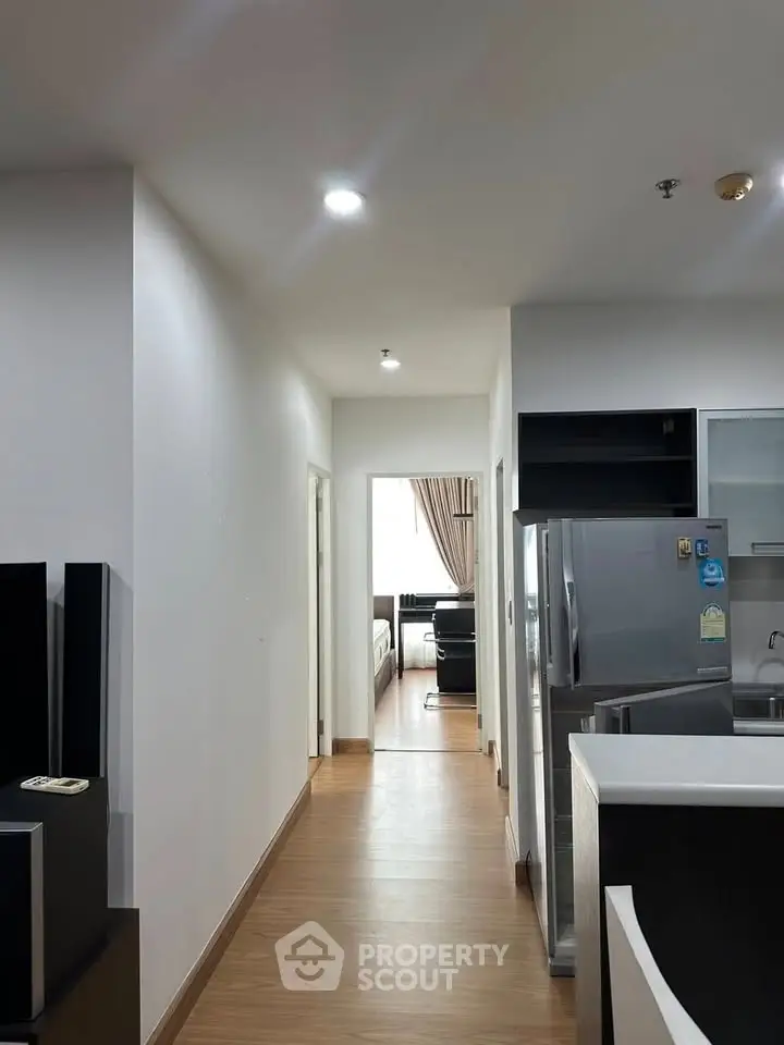 Modern apartment hallway leading to a cozy living room with sleek kitchen appliances.