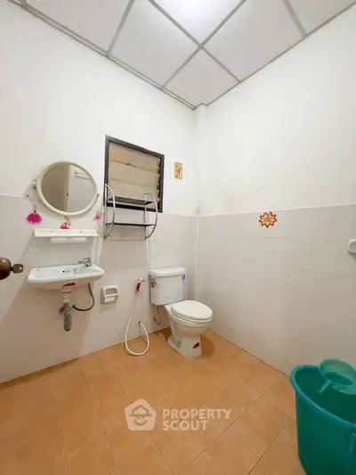 Spacious bathroom with modern fixtures and tiled flooring, featuring a round mirror and a convenient wall-mounted sink.