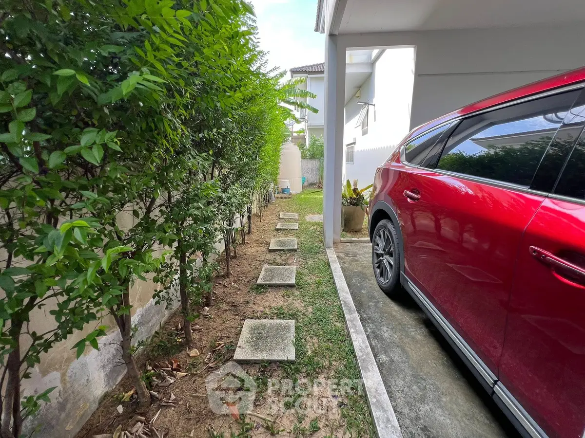 Spacious driveway with red SUV and lush greenery in modern home exterior