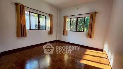 Spacious sunlit room with wooden flooring and large windows
