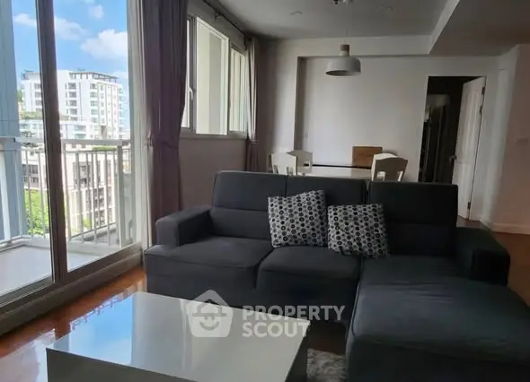 Modern living room with large windows and balcony view in urban apartment.