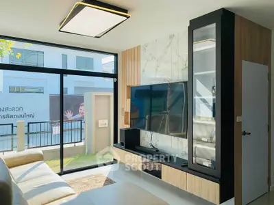 Modern living room with sleek TV setup and large windows offering natural light.