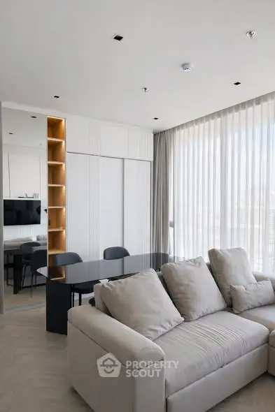 Modern living room with sleek furniture and large windows offering natural light.
