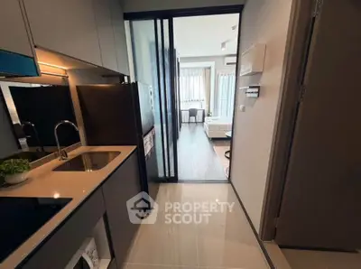 Modern apartment kitchen with sleek design and open layout leading to living area.