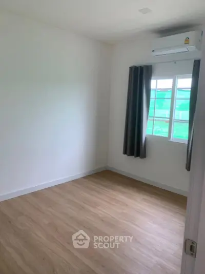 Spacious empty room with wooden flooring and air conditioning, perfect for customization.