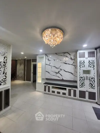 Luxurious living room with elegant chandelier and marble accent wall