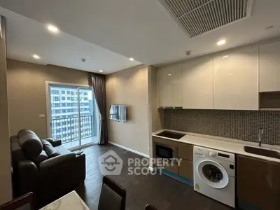 Modern open-layout living room with kitchen, featuring a balcony and sleek appliances.