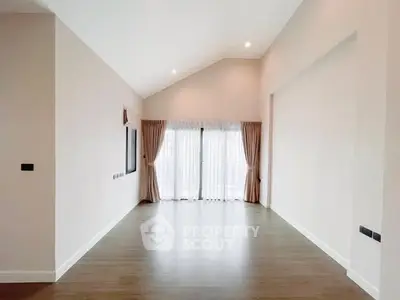 Spacious empty living room with high ceiling and large windows.