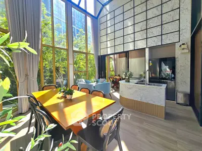 Stunning sunlit dining area with modern kitchen and lush garden view, perfect for entertaining.