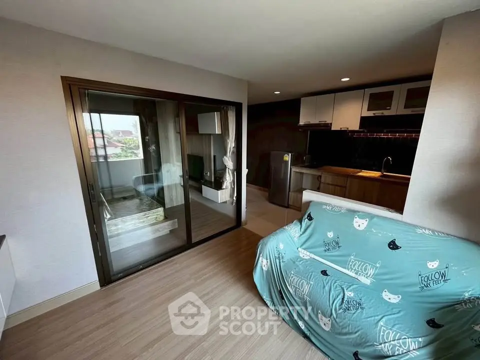 Modern living room with open kitchen and balcony access, featuring stylish decor and natural light.