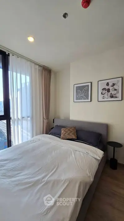 Modern bedroom with large window and stylish decor in a high-rise apartment.