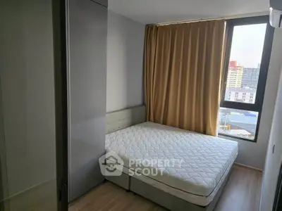 Modern bedroom with large window and city view, featuring a comfortable bed and stylish decor.