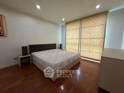 Spacious bedroom with wooden flooring and large windows for natural light