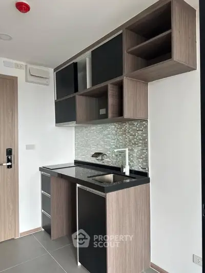 Modern compact kitchen with sleek cabinetry and stylish backsplash in a contemporary apartment.
