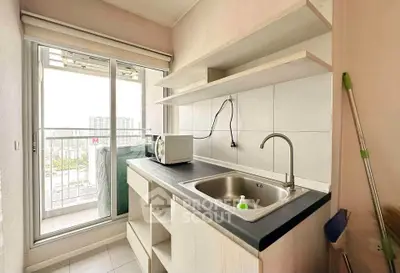 Compact kitchen with open shelving and balcony view, featuring a sleek countertop and modern sink.