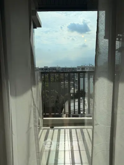 Charming balcony view with sheer curtains and urban skyline, perfect for relaxation.