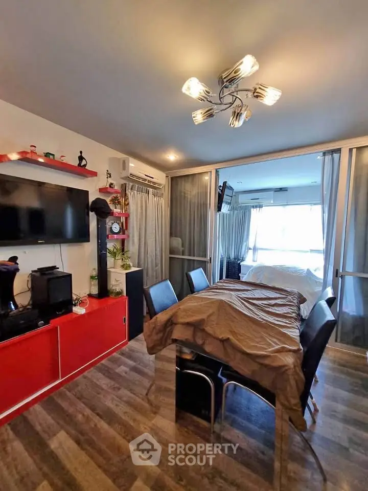 Modern living room with dining area, stylish lighting, and sleek red cabinetry.