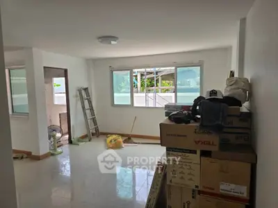 Spacious unfurnished living room with large windows and boxes, ideal for customization.