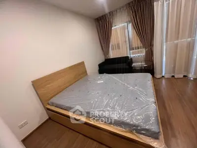 Spacious bedroom with modern wooden bed and cozy seating area, featuring elegant floor-to-ceiling curtains.