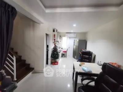 Spacious open-plan living area with modern kitchen and dining space, featuring sleek furniture and festive decor.