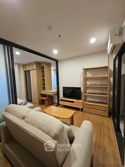 Modern living room with cozy sofa, wooden furniture, and sleek TV setup in a stylish apartment.
