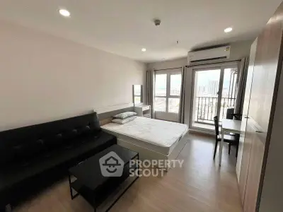 Modern studio apartment with city view, featuring a cozy bed, sleek sofa, and compact workspace.