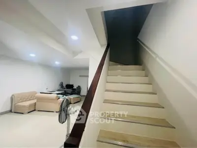 Spacious interior with modern staircase and cozy seating area, ideal for contemporary living.